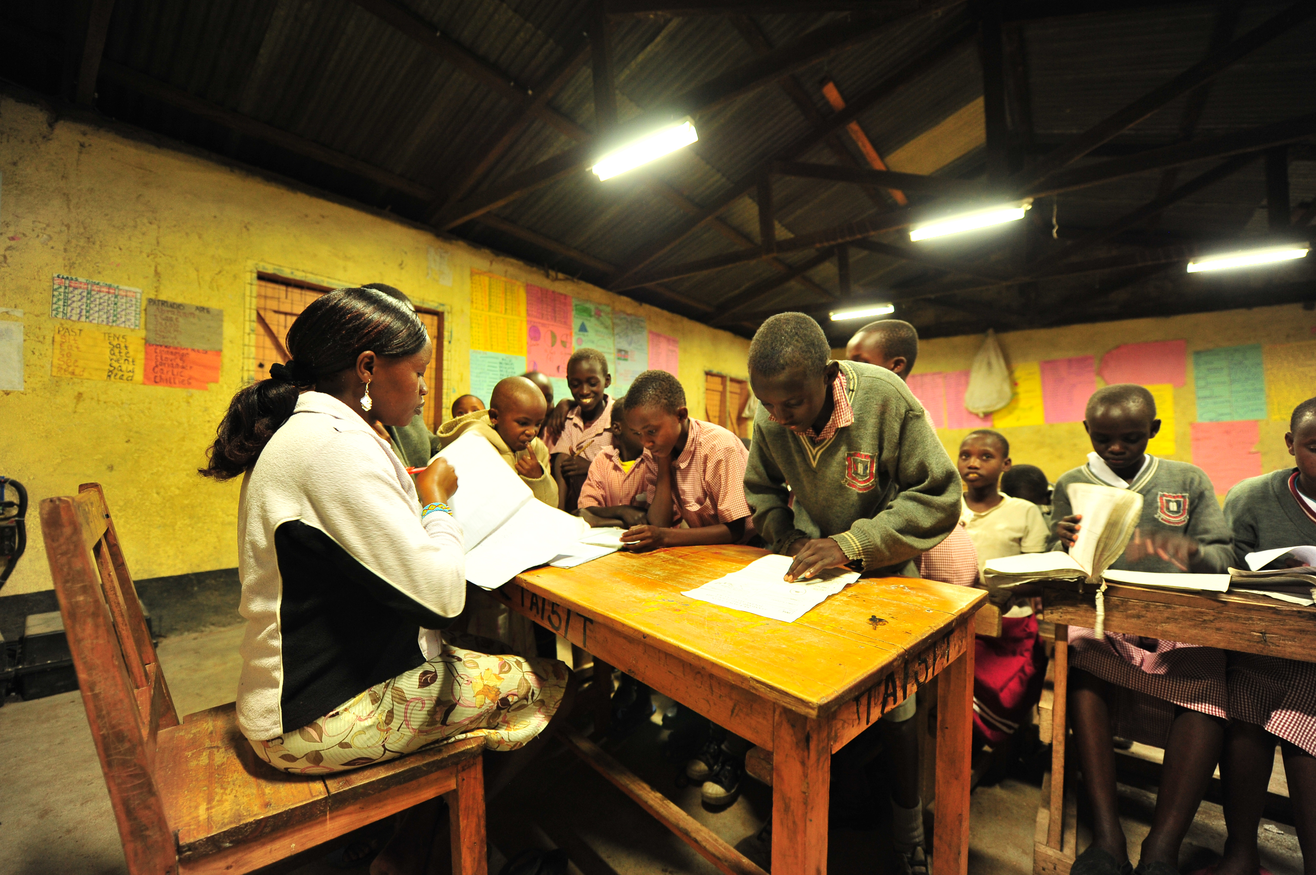 Class teacher Maria marks her pupils' books during night preps at Talek mixed day and boarding primary school. The school relies on its' solar panels for lighting especially after sunset because Talek town is not connected to the national power grid. Residents and business owners in Talek have had to rely on alternative power sources but this is set to change with the Talek Solar Powered Mini Grid. Through Talek Power, GIZ and other partners have constructed a solar power grid which will connect residents of Talek town in Narok to power for domestic and commercial use.