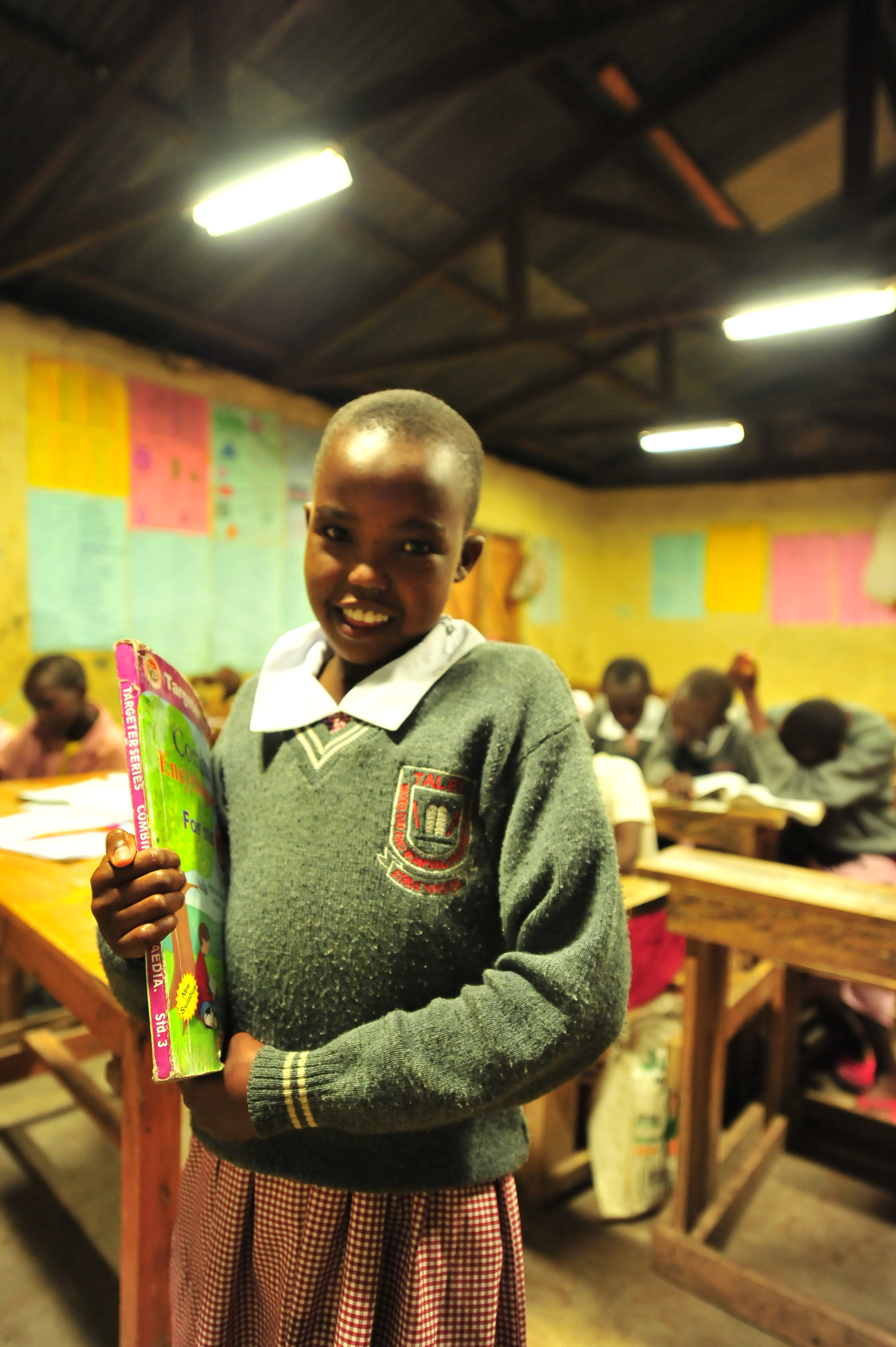 A pupil carries her books to class during night preps at Talek mixed day and boarding primary school. The school relies on its' solar panels for lighting especially after sunset because Talek town is not connected to the national power grid. Residents and business owners in Talek have had to rely on alternative power sources but this is set to change with the Talek Solar Powered Mini Grid. Through Talek Power, GIZ and other partners have constructed a solar power grid which will connect residents of Talek town in Narok to power for domestic and commercial use.