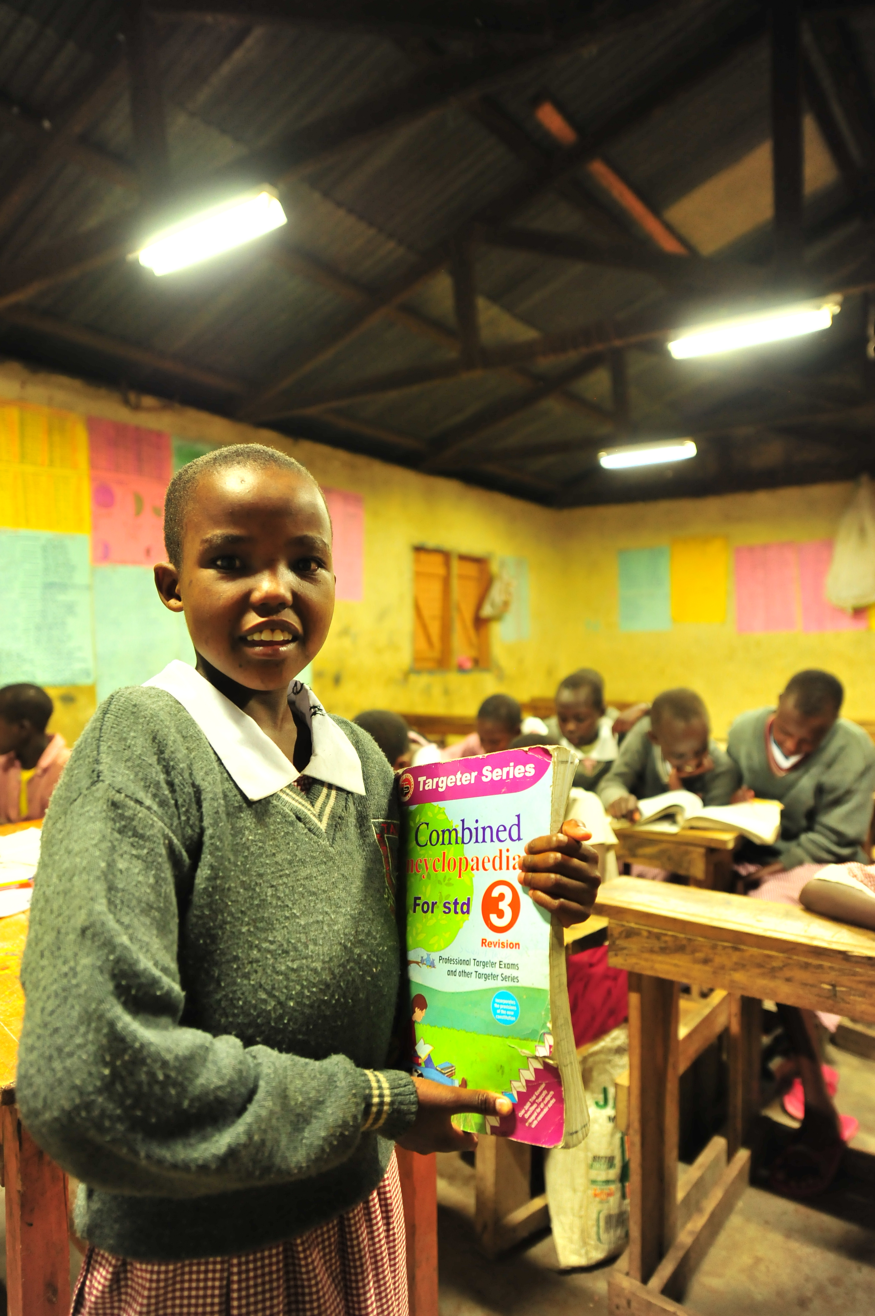 A pupil carries her books to class during night preps at Talek mixed day and boarding primary school. The school relies on its' solar panels for lighting especially after sunset because Talek town is not connected to the national power grid. Residents and business owners in Talek have had to rely on alternative power sources but this is set to change with the Talek Solar Powered Mini Grid. Through Talek Power, GIZ and other partners have constructed a solar power grid which will connect residents of Talek town in Narok to power for domestic and commercial use.